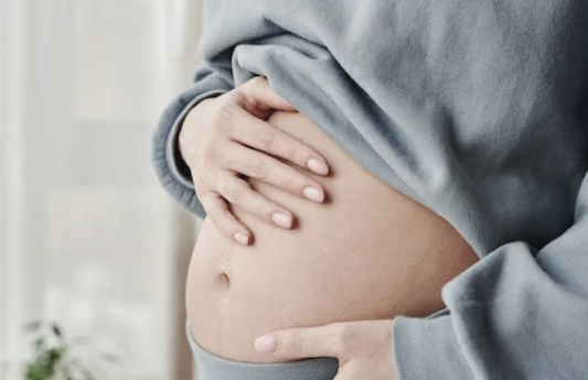 Eine Schwangere Person mit Hand auf dem Bauch
